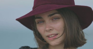 Kırmızı şapkalı güzel kız gülümsüyor, dilini gösteriyor ve oynaşıyor.