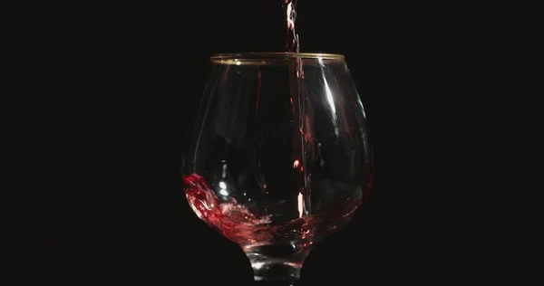 Wlewanie Czerwonego Wina Kieliszka Przed Czarnym Tłem — Zdjęcie stockowe