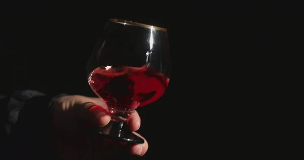 黒の背景の前のソムリエが赤ワインを味わう — ストック写真