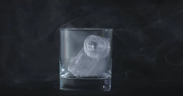 アルコール ウイスキーグラス 煙の氷のキューブが黒い背景に浮かんでいます — ストック写真