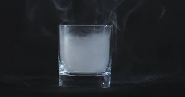 黒い背景と浮遊煙を背景にした空のウイスキー アルコールガラス — ストック写真