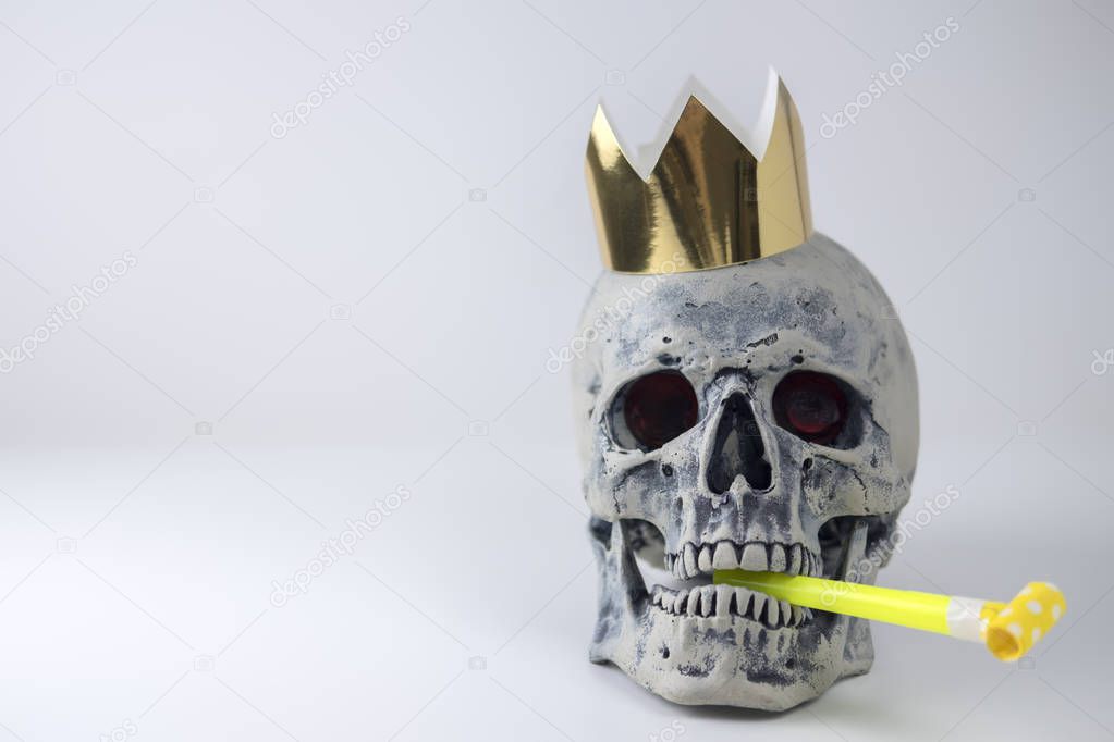 Halloween human gray skull imitation with festive pipe in mouth and golden crown on head. Decorating for holiday Halloween. The concept of eternal holiday.