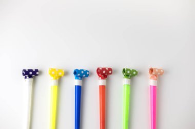 Beyaz bir masanın üzerinde yatan festival çok renkli borular. Minimalist tarzı. Üstten görünüm. Düz yatıyordu. Metin için yer. Boşaltmak.