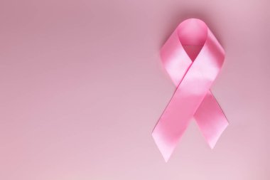 Pembe kurdele kadın meme hastalığı sembolü olarak pembe arka plan üzerinde. Meme kanseri ay farkındalık teyp. Minimalist tarzı. Üstten görünüm. FLET lei. Metin için yer. Kopya alanı.