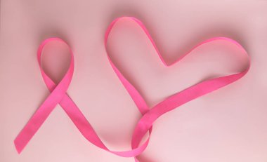 Pembe kurdele ve kalp kadın meme hastalığı sembolü olarak pembe arka plan üzerinde. Meme kanseri ay farkındalık teyp. Minimalist tarzı. Üstten görünüm. FLET lei. Metin için yer. Kopya alanı.