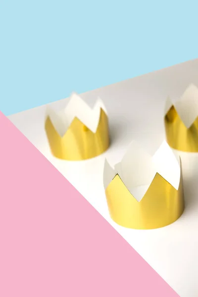 Kartonnen gouden kronen liggend op een witte tafel. Minimalistische stijl. Plek voor tekst. Copyspace. — Stockfoto