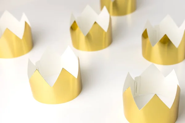 Картонні золоті коронки лежать на білому столі. Мінімалістичний стиль . — стокове фото