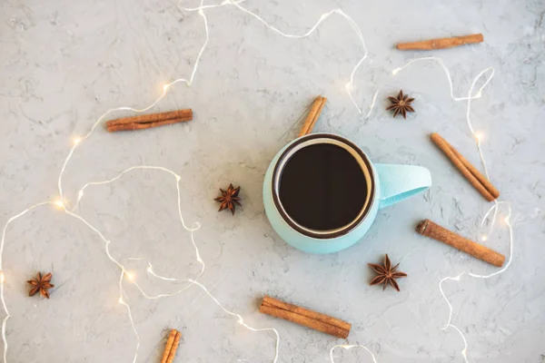 Blue cup of coffee on gray concrete background. Cinnamon sticks, anise stars and garland. Cozy drink autumn and winter concept. Top view. Flat lay. — Stock Photo, Image