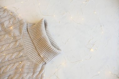 Rahat düz yatıyordu. Sıcak kış ve sonbahar giyim: kazak, eşarp, eldiven beyaz beton dokusal arka planda. Süslemeleri için tatil.