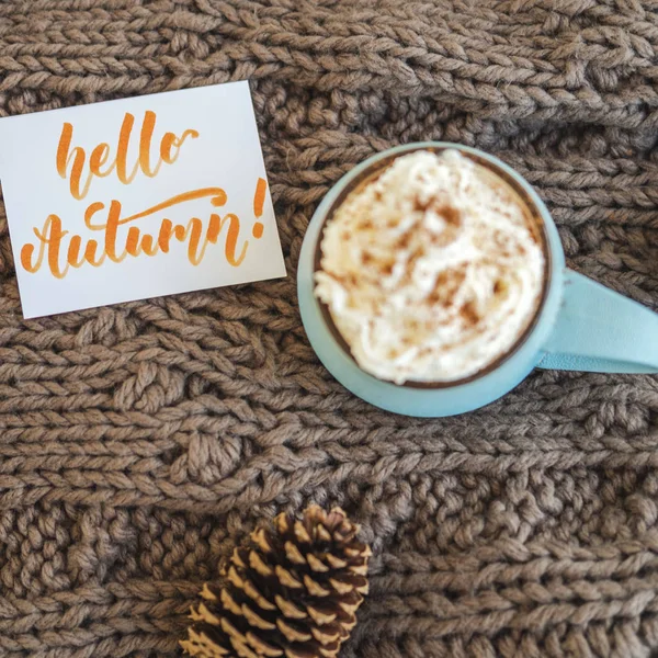 Tasse de café, cacao ou chocolat chaud avec crème fouettée et écharpe à la cannelle avec cône de pin, carte Hello Autumn. Latte à la citrouille - boisson confortable pour l'automne froid ou l'hiver . — Photo