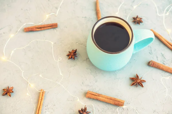 Blue cup of coffee on gray concrete background. Cinnamon sticks, anise stars and garland. Cozy drink autumn and winter concept. Top view. Flat lay. — Stock Photo, Image