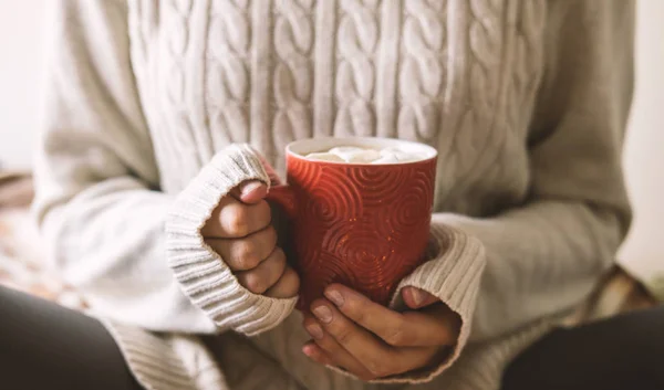 Женские руки в свитере держат чашку горячего кофе, шоколада или чая. зимний комфорт, утреннее питье, тепло посреди холода . — стоковое фото