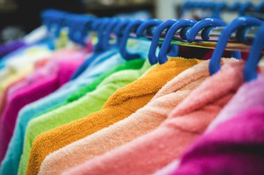 Çok renkli terry cüppe askı da bir satır asılı. Bir mağazada veya pazarda satılık giyim yaratıcı sunumu.