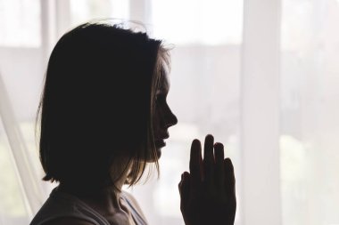 Dua jesti clasped el penceresinde kız silueti.