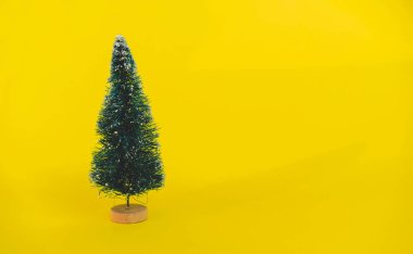 Uzun gölge ile parlak sarı Noel arka plan üzerinde ahşap taban üzerinde Minyatür oyuncak yapay Çam ağacı. Yeni Yıl Kavramı, Noel tatil tebrik kartı.