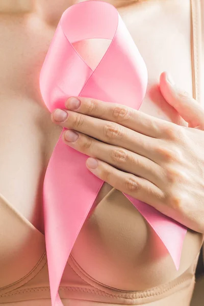 Chica irreconocible en sujetador beige sostiene cinta rosa en su pecho. Concepto para el mes de octubre de concienciación internacional sobre el cáncer de mama . — Foto de Stock