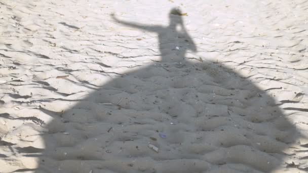 Silueta sobre la arena de una bailarina en un vestido revoloteando en el viento . — Vídeo de stock