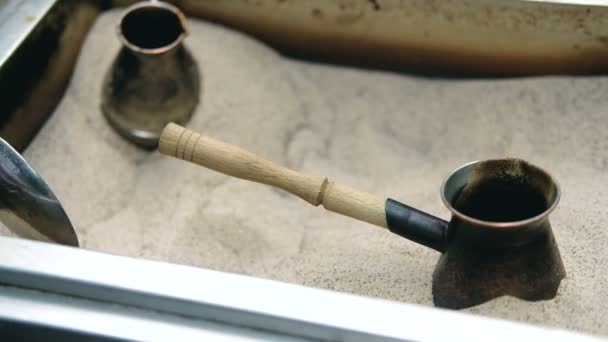 Mans hand holds Turk and prepares Turkish coffee in the sand in it. Slow motion. — Stock Video