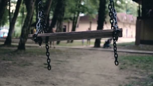 Balançoire vide balançant dans le vent au milieu du parc sombre. Enlèvement conceptuel d'enfants . — Video