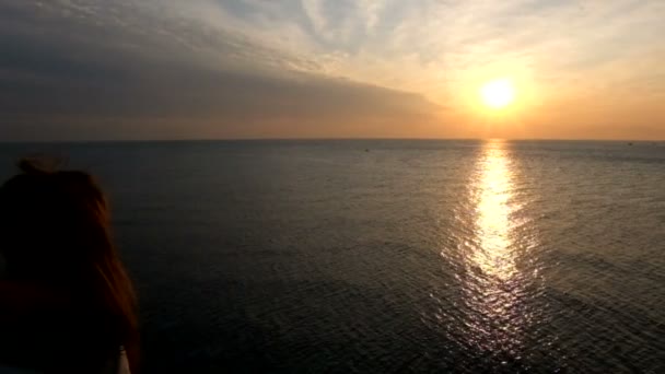 Ragazza irriconoscibile con i capelli lunghi ammirare il tramonto sul mare o sull'oceano. Il sole tramonta nell'acqua . — Video Stock