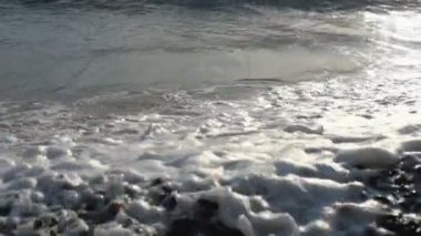 Dalgalar gün batımında deniz veya okyanus kıyısına yuvarlanıyor. Yavaş çekim.