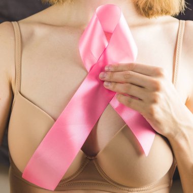 Bej sütyen içinde tanınmayan kız göğsünde pembe kurdele tutar. Uluslararası Meme kanseri farkındalık ayı Ekim için Kavram.