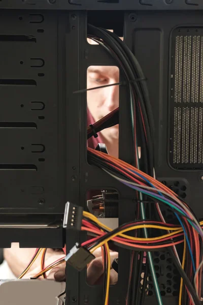 Young man repairs a computer system unit, changes parts, video card and hard drive, sets new components. Computer Repair Wizard.