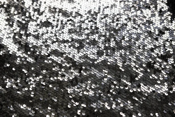 Seksen kumaş dokusu. Parlak gümüş ışıltılı arka plan. Gösterişli bir parti için parıltılı metalik kıyafetler, kutlama. Yakın plan..