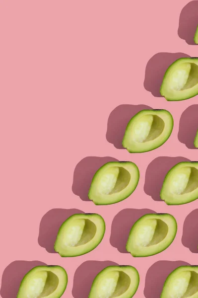 Trending style pattern of half seedless green avocado on pink background with hard light. Creative food texture. — Stock Photo, Image