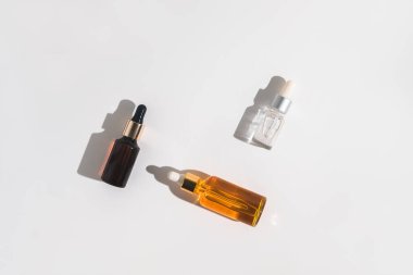 Beyaz arka planda beyaz, turuncu ve siyah serum şişeleri. Kozmetik modeli. Metin ve resimler eklenecek yer. Üst Manzara. Düz yatıyordu.