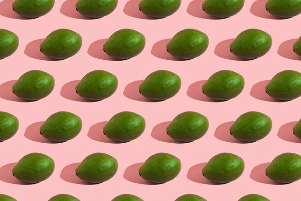 Трендовый узор в стиле цельного зеленого авокадо на розовом фоне с жестким светом. Творческая текстура продуктов питания. — стоковое фото