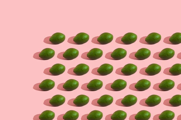 밝은 색의 핑크 색 배경에 있는 전체 녹색 아보카도의 트랜 칭 스타일. 창의적 인 음식 질감. — 스톡 사진
