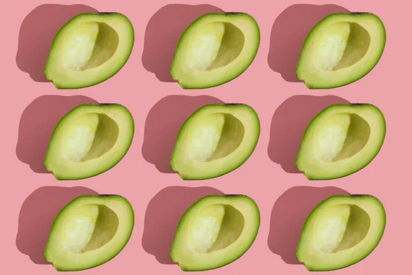 Patrón de estilo de tendencia de aguacate verde medio sin semillas sobre fondo rosa con luz dura. Textura creativa de alimentos. —  Fotos de Stock