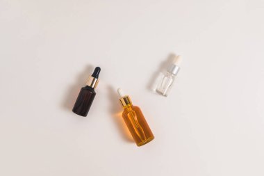 Beyaz arka planda beyaz, turuncu ve siyah serum şişeleri. Kozmetik modeli. Metin ve resimler eklenecek yer. Üst Manzara. Düz yatıyordu.