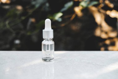 Gri beton arka planda doğal ışık ile şeffaf renkli serum şişeleri. Moda tarzı. Kozmetik modeli. Kopyalama alanı.