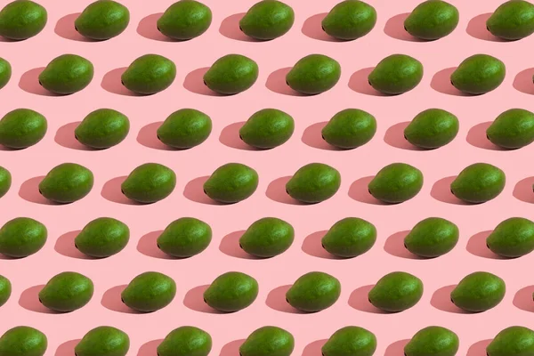 밝은 색의 핑크 색 배경에 있는 전체 녹색 아보카도의 트랜 칭 스타일. 창의적 인 음식 질감. — 스톡 사진