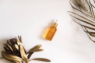 Beyaz arka planda beyaz, turuncu ve siyah serum şişeleri. Palmiye ve protanın altın dalları. Kozmetik modeli. Metin ve resimler eklenecek yer. Üst Manzara. Düz yatıyordu.