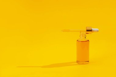 Parlak sarı arka planda parlak ışık gölgesiyle turuncu renkli serum şişeleri. Moda tarzı. Kozmetik modeli. Kopyalama alanı