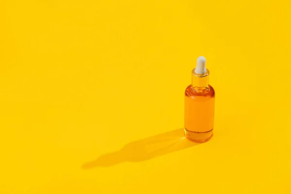 Orange color serum bottles on bright illuminating yellow background with hard light shadow. Trendy style. Cosmetic mockup. Copyspace — Stock Photo, Image