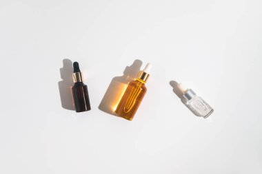 Beyaz arka planda beyaz, turuncu ve siyah serum şişeleri. Kozmetik modeli. Metin ve resimler eklenecek yer. Üst Manzara. Düz yatıyordu.
