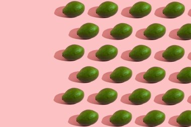 Pembe arka planda yeşil bir avokadonun modaya uygun modeli. Yaratıcı gıda dokusu.