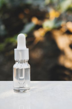 Gri beton arka planda doğal ışık ile şeffaf renkli serum şişeleri. Moda tarzı. Kozmetik modeli. Kopyalama alanı.