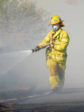 Melbourne, Avustralya - 13 Nisan 2018: itfaiyeci banliyö yüzölçümü Knox şehir Melbourne Doğu bush yangın, bir hortum ile.
