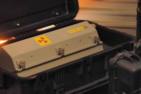 Box shaped metal container with radiation warning in a military grade transport box under red light