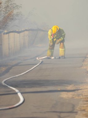 Melbourne, Avustralya - 13 Nisan 2018: itfaiyeci banliyö yüzölçümü Knox şehir Melbourne Doğu bush yangın, bir hortum ile.