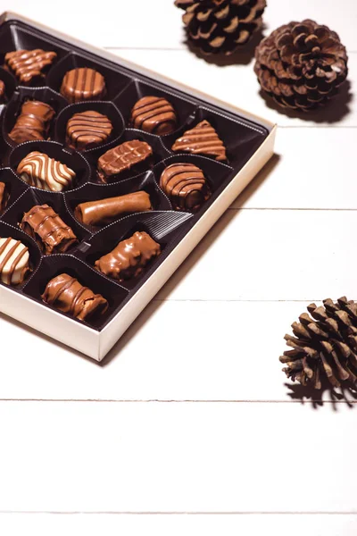 A lot of variety chocolates in box on white wooden background