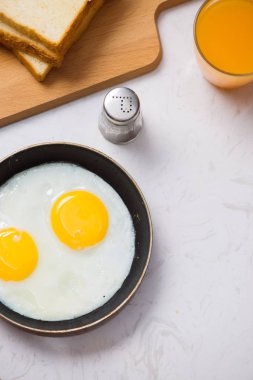 Bu süreç içinde yemek, yumurta bir kızartma tavası, tost ve portakal suyu beyaz bir arka plan günü kahvaltıda kızarmış. Gün ışığı.
