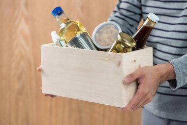 Gönüllü bağış kutusu ahşap arka plan üzerinde gıda maddeleri ile tutarak