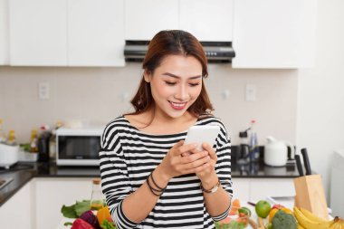 modern mutfakta otururken cep telefonu kullanan kadın