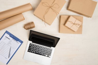 Laptop ve teslim alış irsaliyesiyle masada çalışan teslimatçı üstten görünüm